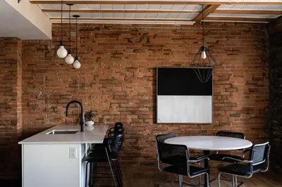 a kitchen with a table and chairs against a brick wall at Maison Place Royale by Luxury In Transit in Montréal