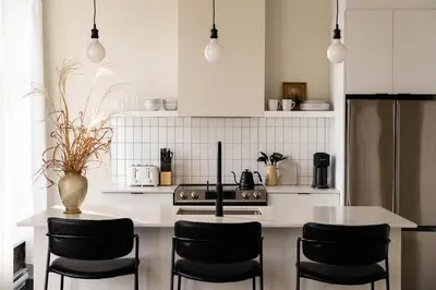 a kitchen with a white counter and black chairs at Maison Place Royale by Luxury In Transit in Montréal