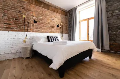 a bedroom with a brick wall and a large bed at Maison Place Royale by Luxury In Transit in Montréal