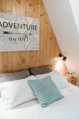 a bedroom with a bed with a sign on the wall at Le Grizzli Orford in Orford