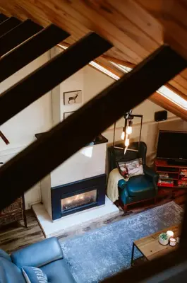 a living room with a fireplace and a chair at Le Grizzli Orford in Orford