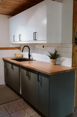 a kitchen with white cabinets and a wooden counter top at Le Grizzli Orford in Orford