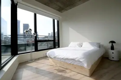 a white bedroom with a bed and large windows at Appartement de luxe avec piscine in Montréal