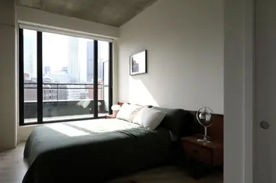 a bedroom with a bed and a large window at Appartement de luxe avec piscine in Montréal