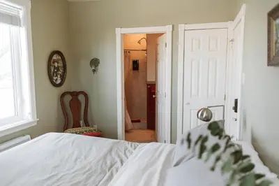 a bedroom with a white bed and a bathroom at Auberge Incroyable in Saint Adrien