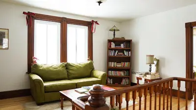 a living room with a green couch and a book shelf at Auberge Incroyable in Saint Adrien