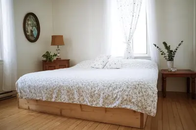 a bedroom with a bed with a white blanket and a window at Auberge Incroyable in Saint Adrien