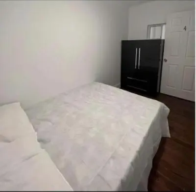 a white bed in a room with a black refrigerator at Self-service small breakfast private Room 1 in Montréal