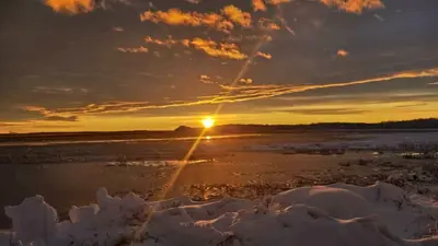a sunset over a snowy field with the sun in the sky at Loft in Louiseville