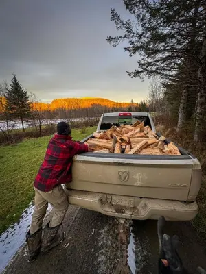 a man loading logs into the back of a truck at Mont Megantic - Chalet Le Madison in La Patrie