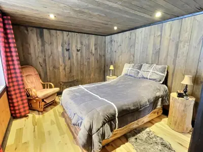 a bedroom with a bed and a wooden wall at Mont Megantic - Chalet Le Madison in La Patrie