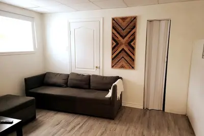 a living room with a brown couch and a door at Cozy 1BR in Vieux-Longueuil +parking 14min Downtown in Longueuil