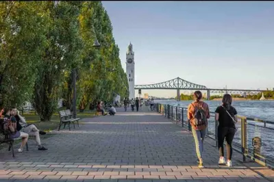 a group of people walking on a sidewalk near the water at Cozy 1BR in Vieux-Longueuil +parking 14min Downtown in Longueuil
