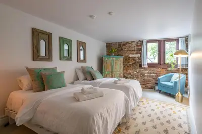 two large beds in a bedroom with a blue chair at Exclusive 6 bed, 6 bath residence in Old Montreal in Montréal
