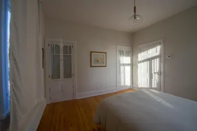 a white bedroom with a bed and a window at Pignon sur Parc in Trois-Rivières