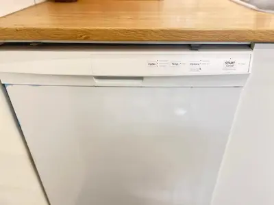 a white dishwasher under a counter in a kitchen at Basement 2-bedroom apartment near National Park and Montréal in Saint-Bruno-de-Montarville