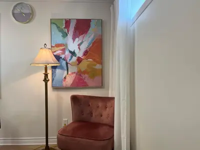 a lamp and a chair in a room with a painting at Basement 2-bedroom apartment near National Park and Montréal in Saint-Bruno-de-Montarville
