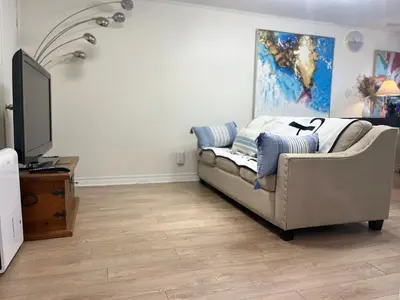 a living room with a couch and a flat screen tv at Basement 2-bedroom apartment near National Park and Montréal in Saint-Bruno-de-Montarville