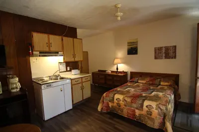 a bedroom with a bed and a kitchen with a stove at Motel Lennoxville in Sherbrooke