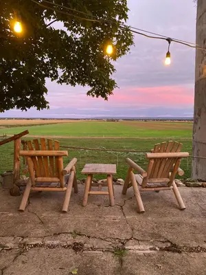 two wooden benches and a picnic table with a field at Eco Lodge Bûcheron Bergère in Ormstown