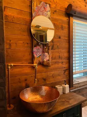 a bathroom with a copper sink and a mirror at Eco Lodge Bûcheron Bergère in Ormstown