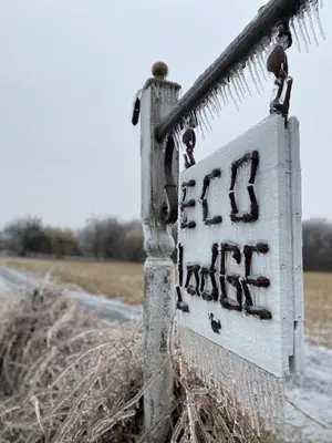 a snow covered sign on a fence in a field at Eco Lodge Bûcheron Bergère in Ormstown