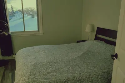 a bedroom with a bed and a window at Cozy 2BR in VieuxLongueuil +parking 14min Downtown in Longueuil