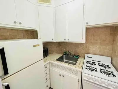 a kitchen with white cabinets and a stove and a sink at Stylish Montreal Apartment: Comfortable Stay in the Golden Square Mile in Montréal