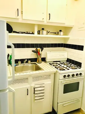 a white kitchen with a sink and a stove at Stylish Montreal Apartment: Comfortable Stay in the Golden Square Mile in Montréal
