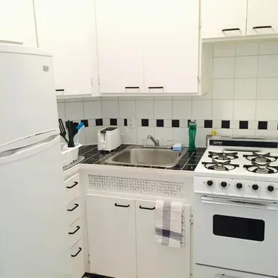 a white kitchen with a stove and a sink at Stylish Montreal Apartment: Comfortable Stay in the Golden Square Mile in Montréal