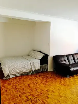 a room with two beds and a leather couch at Stylish Montreal Apartment: Comfortable Stay in the Golden Square Mile in Montréal