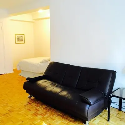 a black leather couch in a room with a bed at Stylish Montreal Apartment: Comfortable Stay in the Golden Square Mile in Montréal