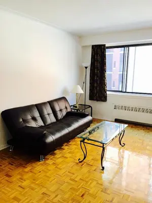 a living room with a black leather couch and a glass table at Stylish Montreal Apartment: Comfortable Stay in the Golden Square Mile in Montréal