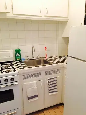 a white kitchen with a sink and a refrigerator at Stylish Montreal Apartment: Comfortable Stay in the Golden Square Mile in Montréal