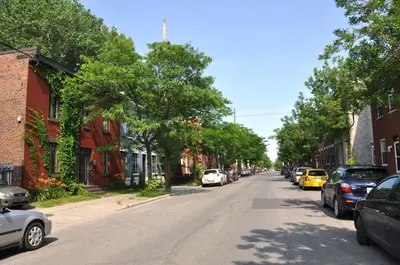 a street in a small town with cars parked at Le Tierra del Fuego by HomeInMontreal in Montréal