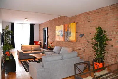 a living room with a couch and a brick wall at Le Metro Mont-Royal by HomeInMontreal in Montréal