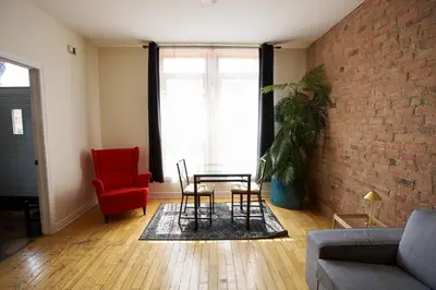 a living room with a brick wall and a table and chairs at Le Metro Mont-Royal by HomeInMontreal in Montréal
