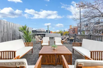 a patio with white chairs and a wooden table at Lofts de la petite Italie in Montréal