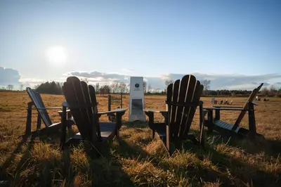two adirondack chairs and a table in a field at MiniBora Le beaumier - Cantons-de-l'Est in Bury