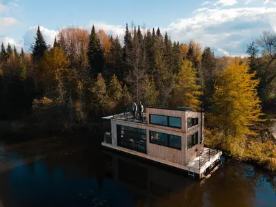 two people standing on a house on a dock in the water at MiniBora Le lichen - Cantons-de-l'Est in Bury