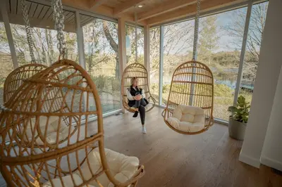 a woman sitting in two swinging chairs in a room with windows at MiniBora Le ciel - Cantons-de-l'Est in Bury