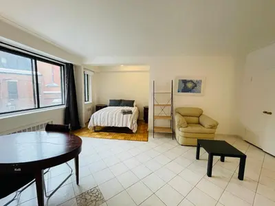 a living room with a bed and a chair at Stylish Montreal Apartment: Comfortable Stay in the Golden Square Mile in Montréal