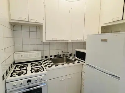 a white kitchen with a stove and a sink at Stylish Montreal Apartment: Comfortable Stay in the Golden Square Mile in Montréal