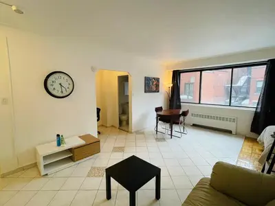 a living room with a clock on the wall at Stylish Montreal Apartment: Comfortable Stay in the Golden Square Mile in Montréal