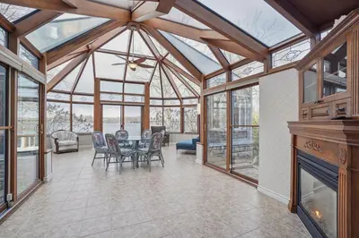 a conservatory with a table and chairs and windows at Private Waterfront Villa 9 BR Peaceful in Laval