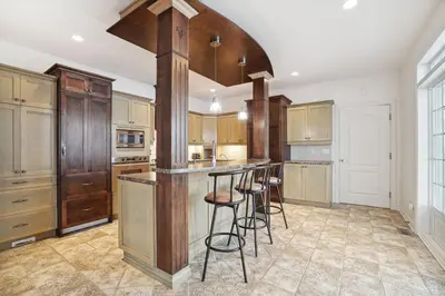 a kitchen with wooden cabinets and a island with bar stools at Private Waterfront Villa 9 BR Peaceful in Laval