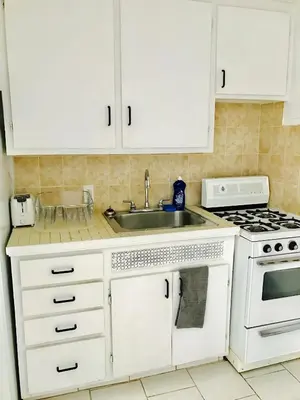 a kitchen with white cabinets and a sink at Stylish Montreal Apartment: Comfortable Stay in the Golden Square Mile in Montréal