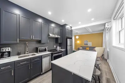 a kitchen with black cabinets and a white counter top at Modern and cozy 4 bedrooms sleep 12 in Montréal