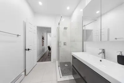 a white bathroom with a shower and a sink at Modern and cozy 4 bedrooms sleep 12 in Montréal