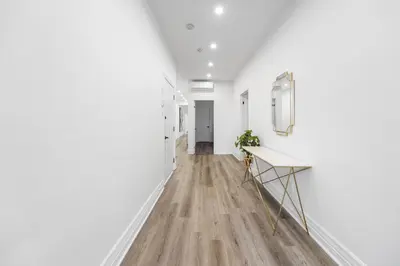 a hallway with white walls and wood floors and a bench at Modern and cozy 4 bedrooms sleep 12 in Montréal